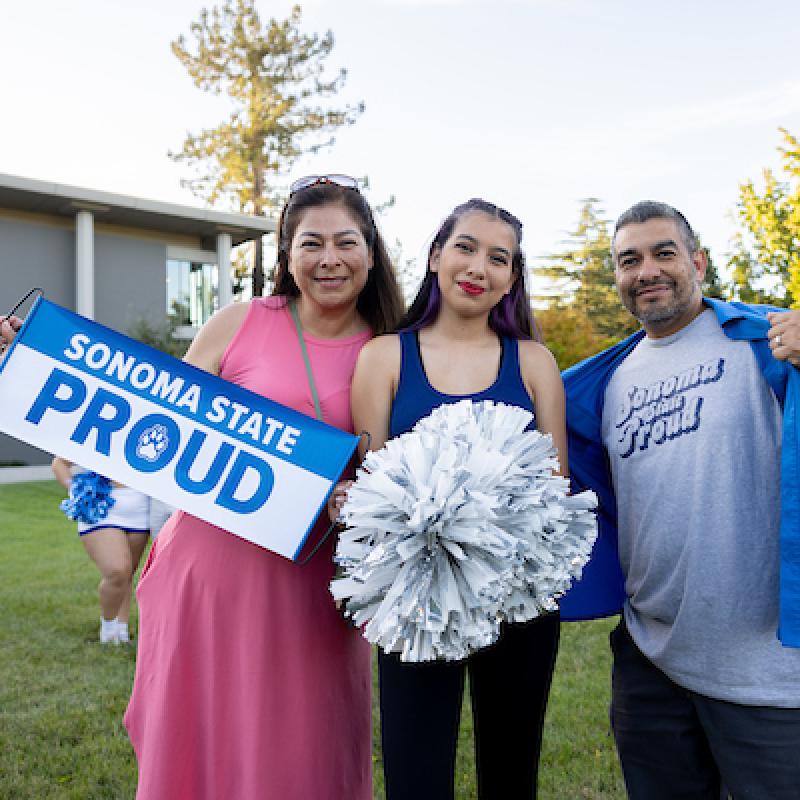 Two parents and student holding a Sonoma State proud banner